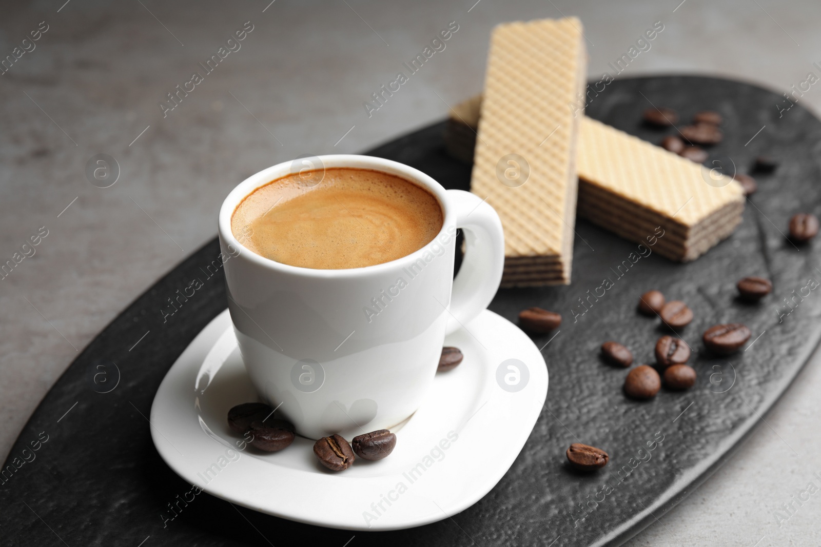 Photo of Delicious coffee and wafers for breakfast on grey table