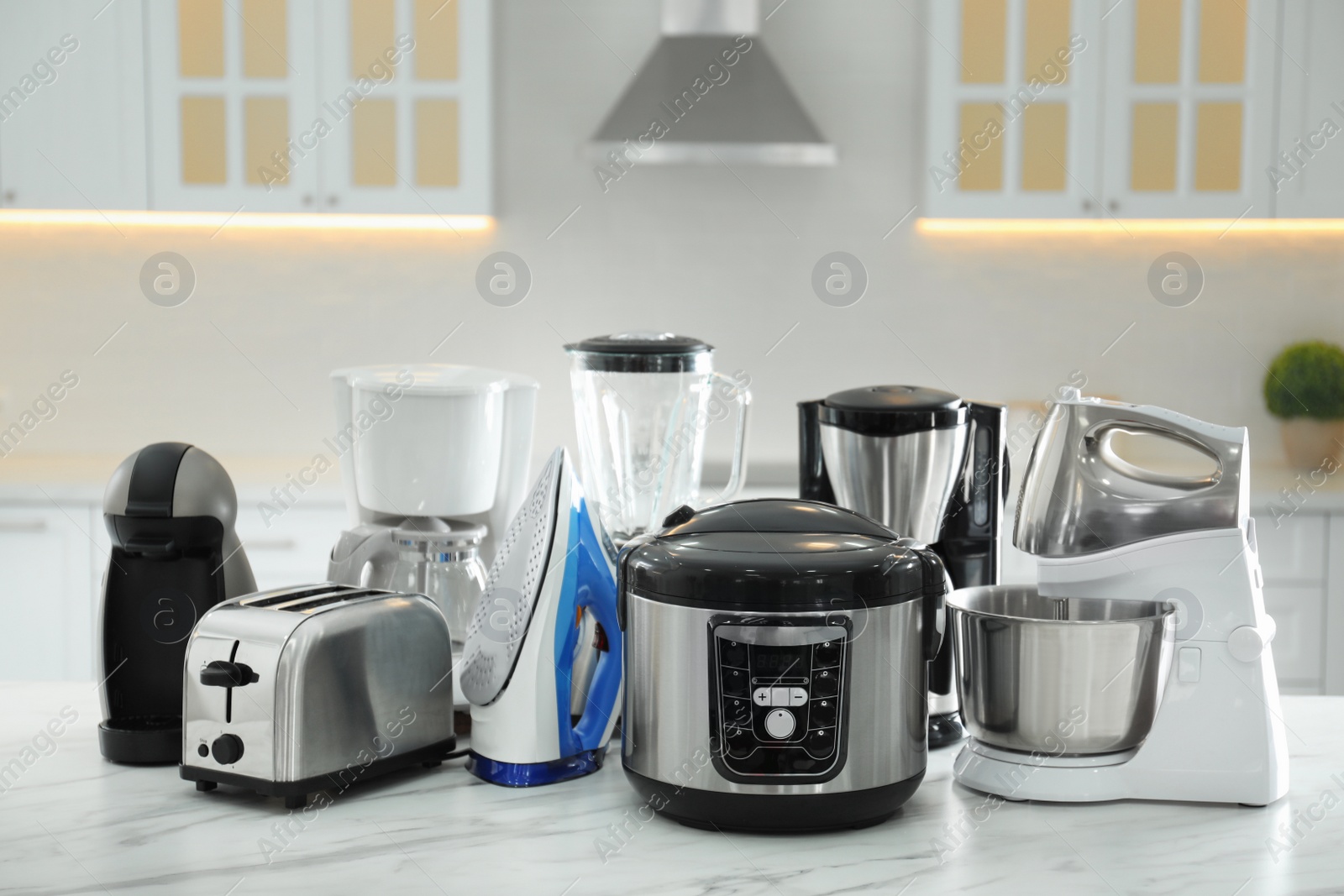 Photo of Set of modern home appliances on white marble table in kitchen