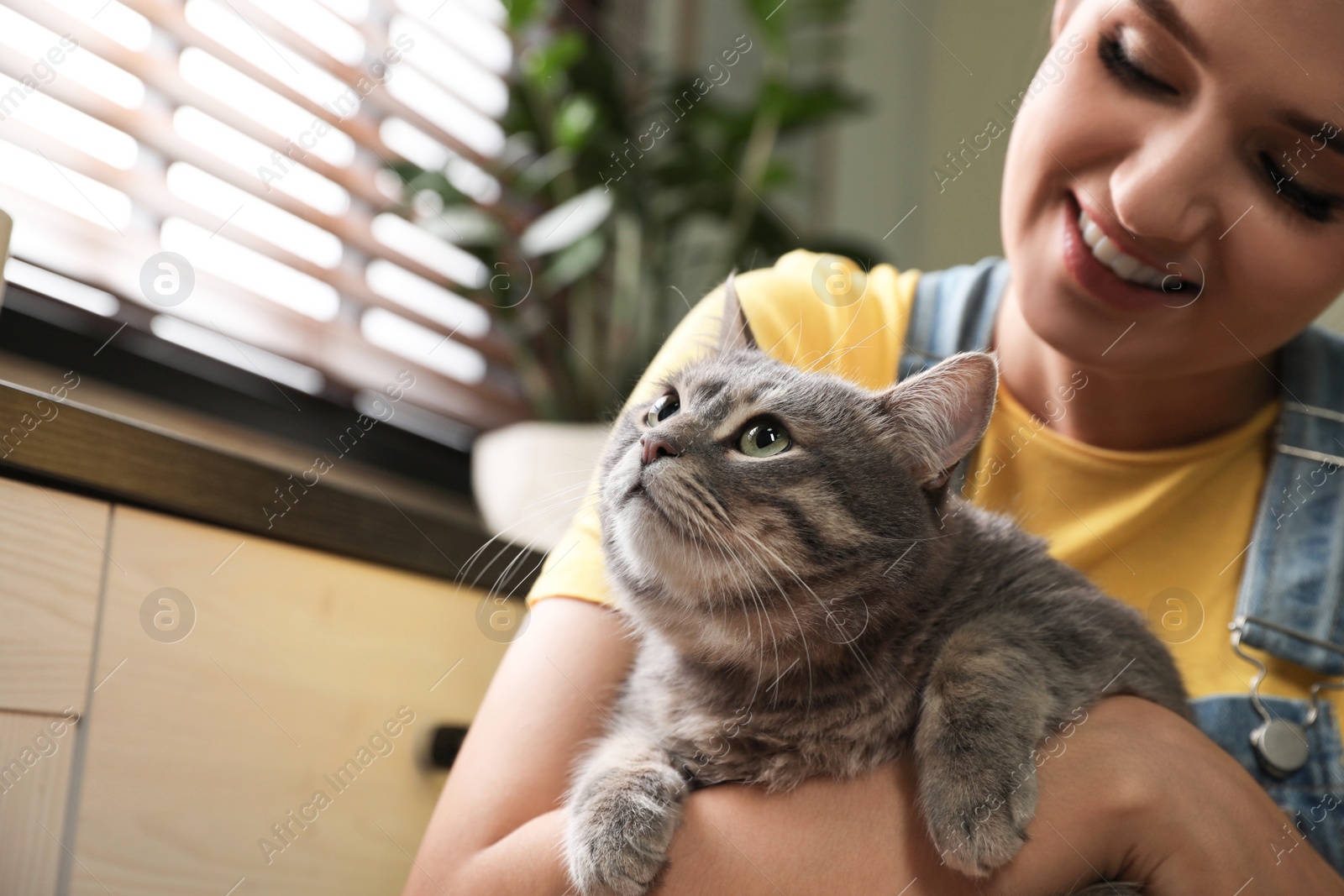 Photo of Young woman with cute cat at home, space for text. Pet and owner