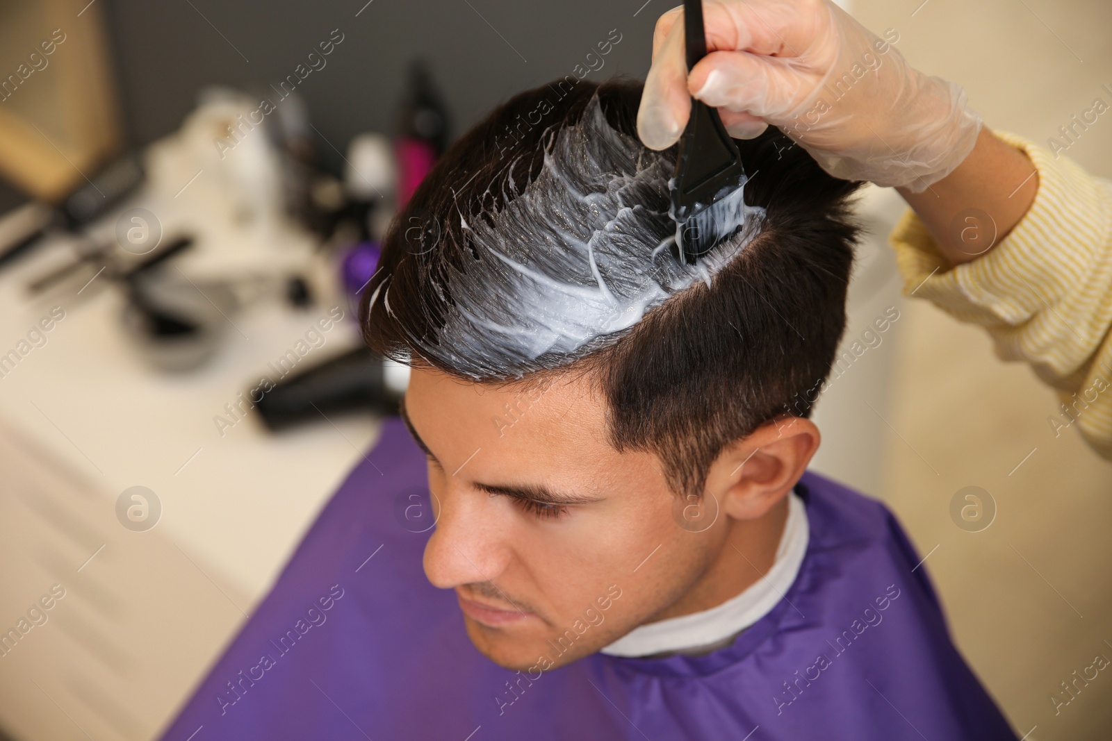 Photo of Professional hairdresser dying hair in beauty salon, closeup
