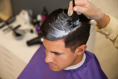Photo of Professional hairdresser dying hair in beauty salon, closeup