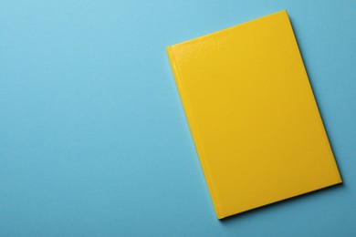 Photo of New yellow planner on light blue background, top view. Space for text