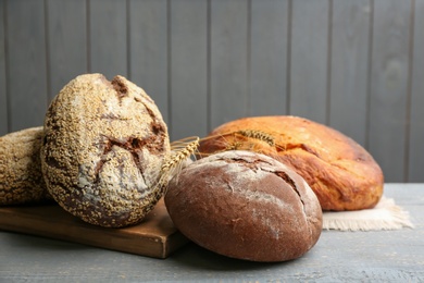 Photo of Loaves of delicious fresh bread on grey wooden table