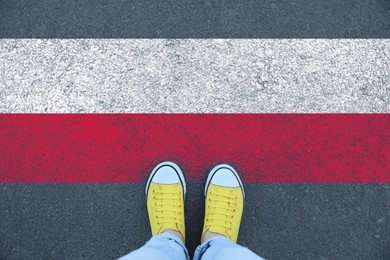 Image of Immigration. Woman standing on asphalt near flag of Poland, top view