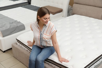 Smiling woman sitting on orthopedic mattress in store