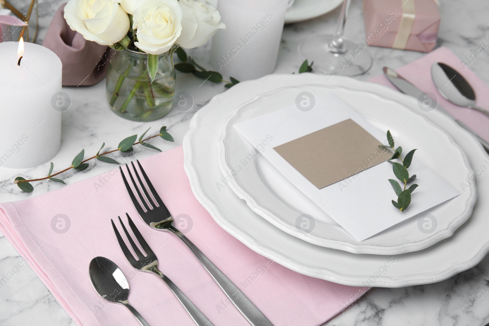 Photo of Elegant festive table setting with blank card on white marble background