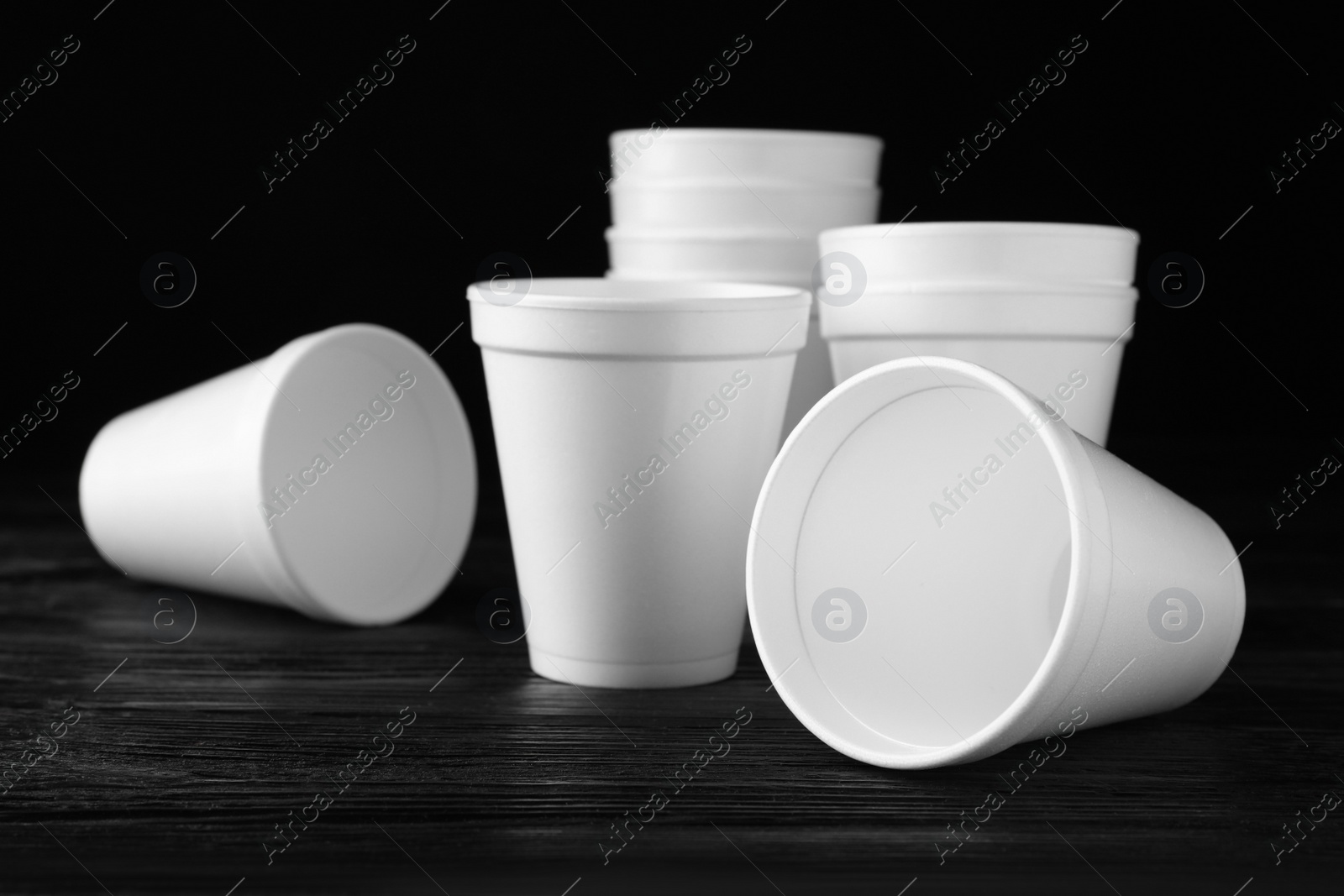 Photo of Many white styrofoam cups on black wooden table, closeup