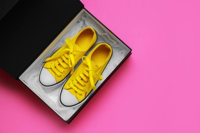 Photo of Comfortable sports shoes in cardboard box on pink background, top view. Space for text