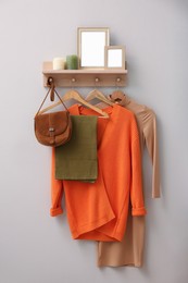 Photo of Wooden shelf, fashionable clothes and decorative elements on beige wall indoors. Interior design