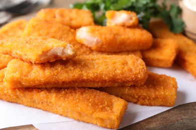 Photo of Tasty fresh fish fingers on wooden board, closeup