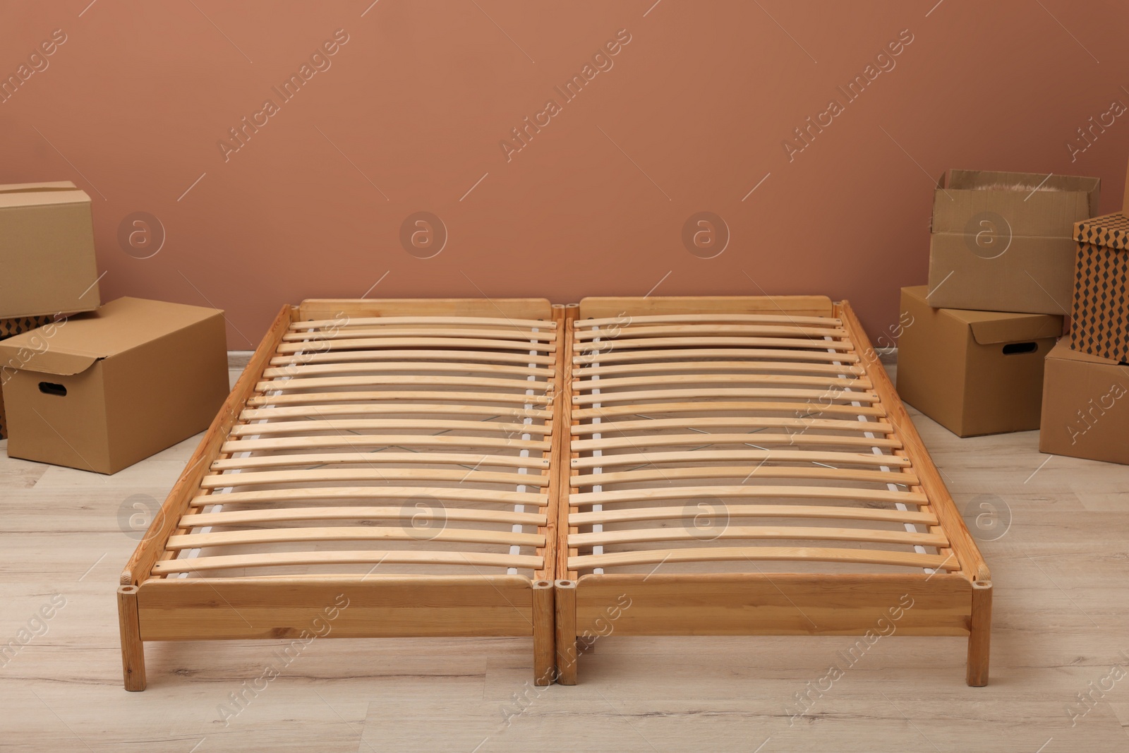 Photo of Wooden bed frame and cardboard boxes on floor in room