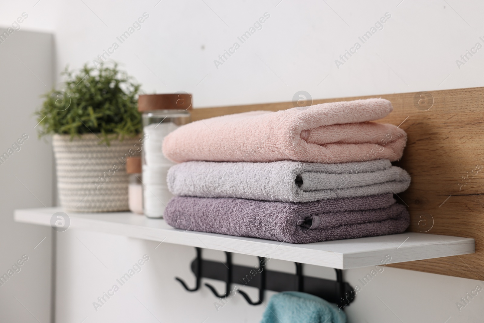 Photo of Fresh towels, houseplant and toiletries on shelf indoors