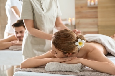 Romantic young couple enjoying herbal bag massage in spa salon