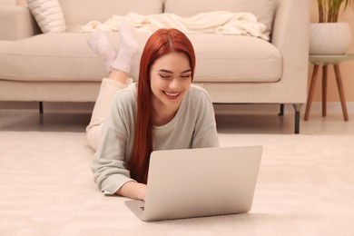 Photo of Happy woman with red dyed hair using laptop at home