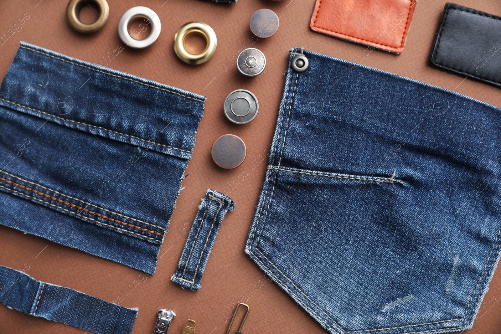 Photo of Flat lay composition with garment accessories and cutting details for jeans on brown background