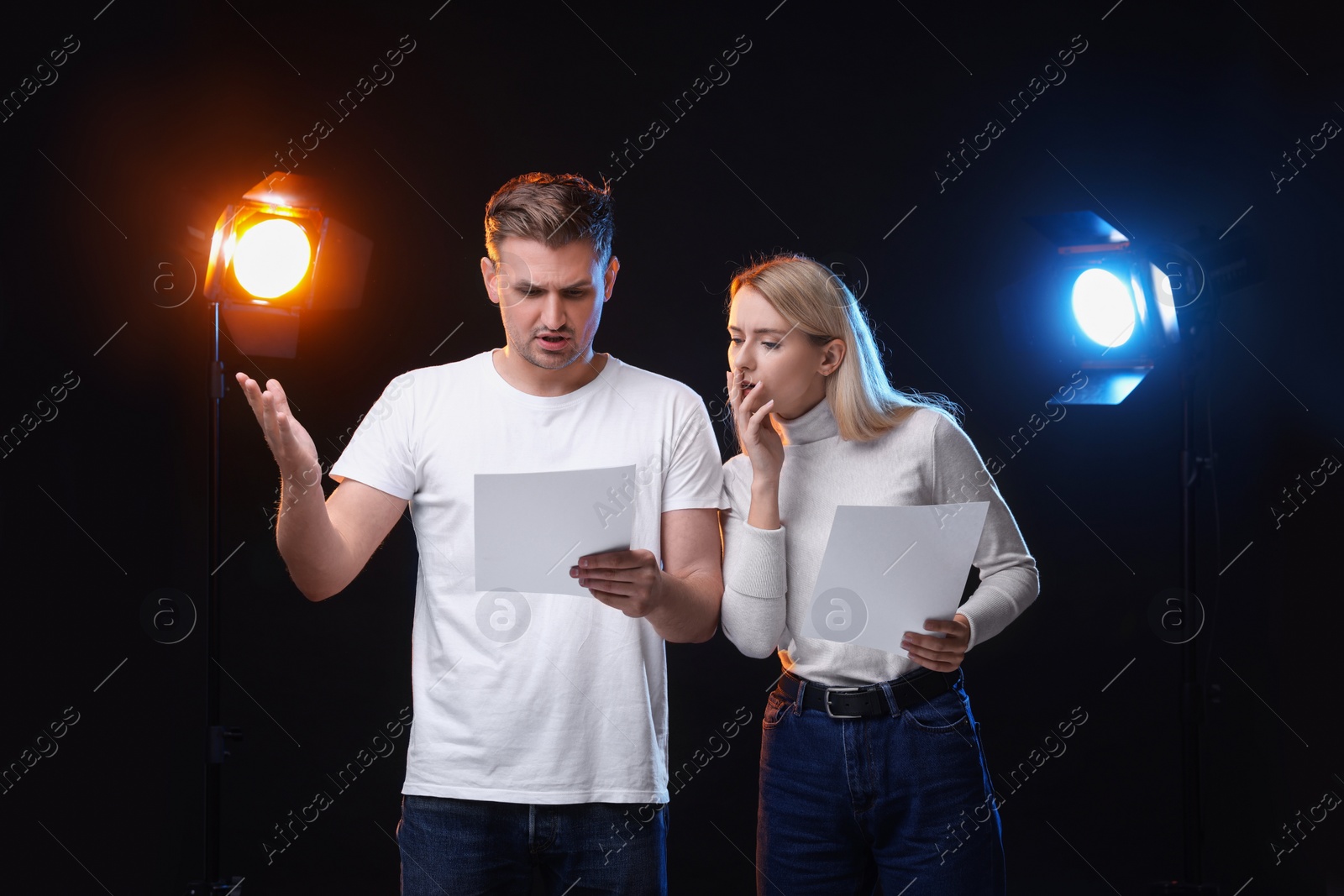 Photo of Casting call. Emotional woman and man with script performing on black background