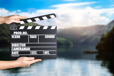 Assistant holding clapperboard outdoors, closeup. Cinema production 