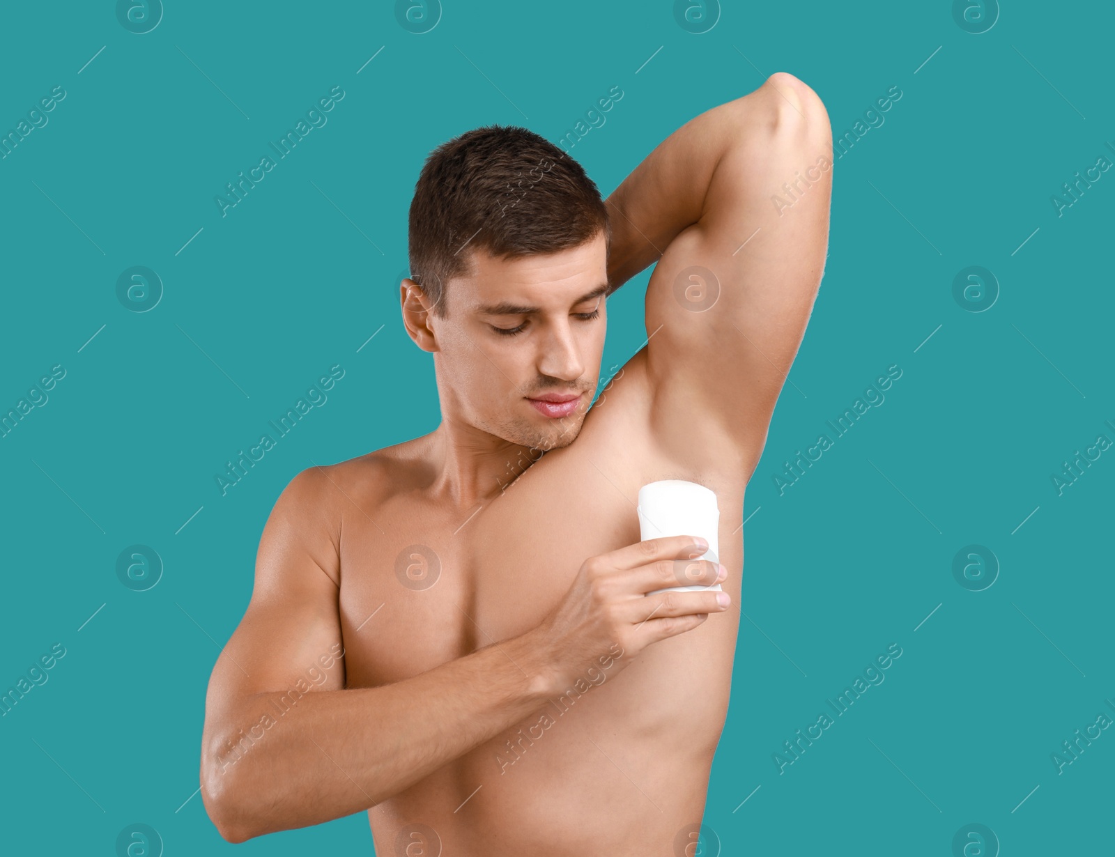 Photo of Young man applying deodorant to armpit on light blue background