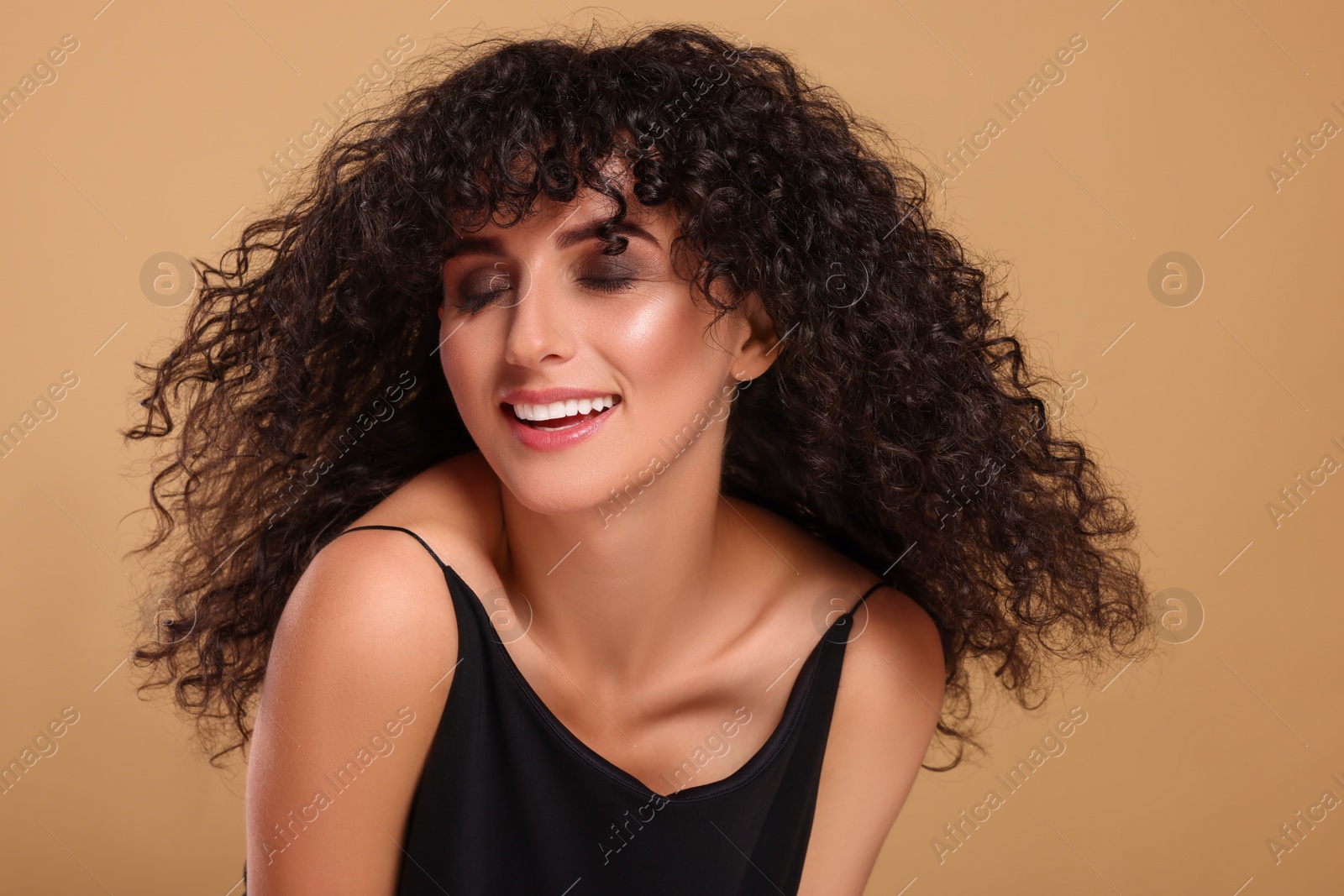 Photo of Beautiful young woman with long curly hair on beige background