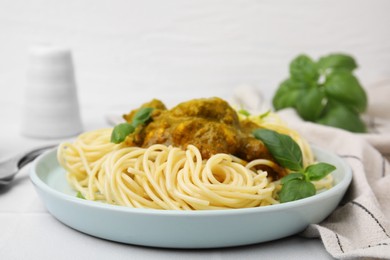 Delicious pasta and chicken with curry sauce served on white tiled table, closeup