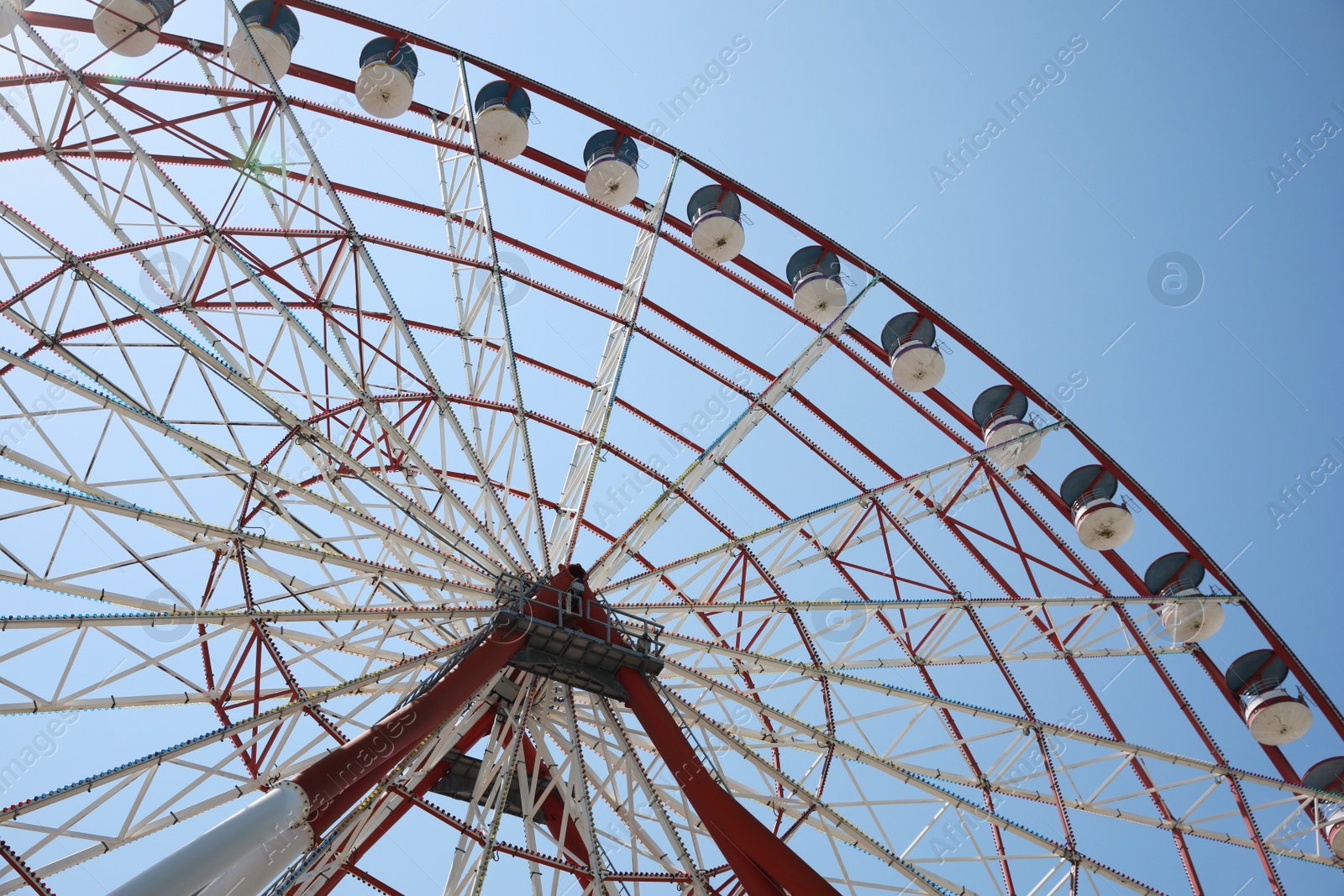 Photo of Beautiful large Ferris wheel against blue sky, low angle view