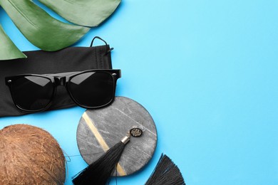 Photo of Flat lay composition with stylish sunglasses and black cloth bag on light blue background. Space for text