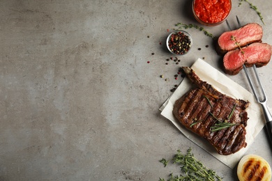 Photo of Flat lay composition with grilled meat steak on grey table. Space for text