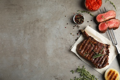 Flat lay composition with grilled meat steak on grey table. Space for text