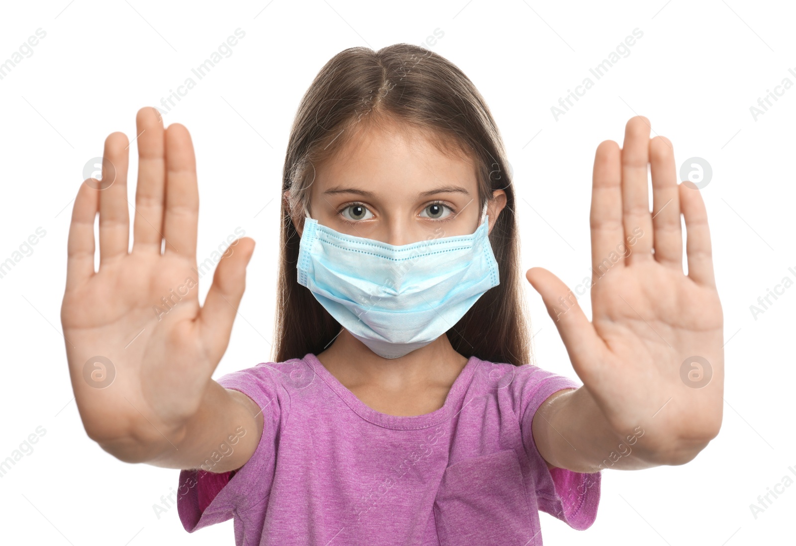 Photo of Little girl in protective mask showing stop gesture on white background. Prevent spreading of coronavirus