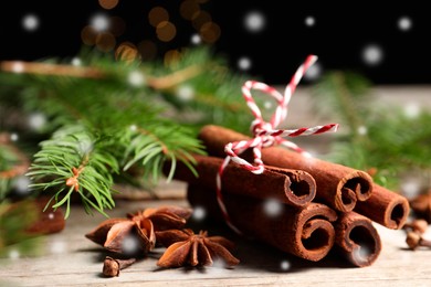 Different spices and fir tree branches on white wooden table, closeup. Cinnamon, anise, cloves