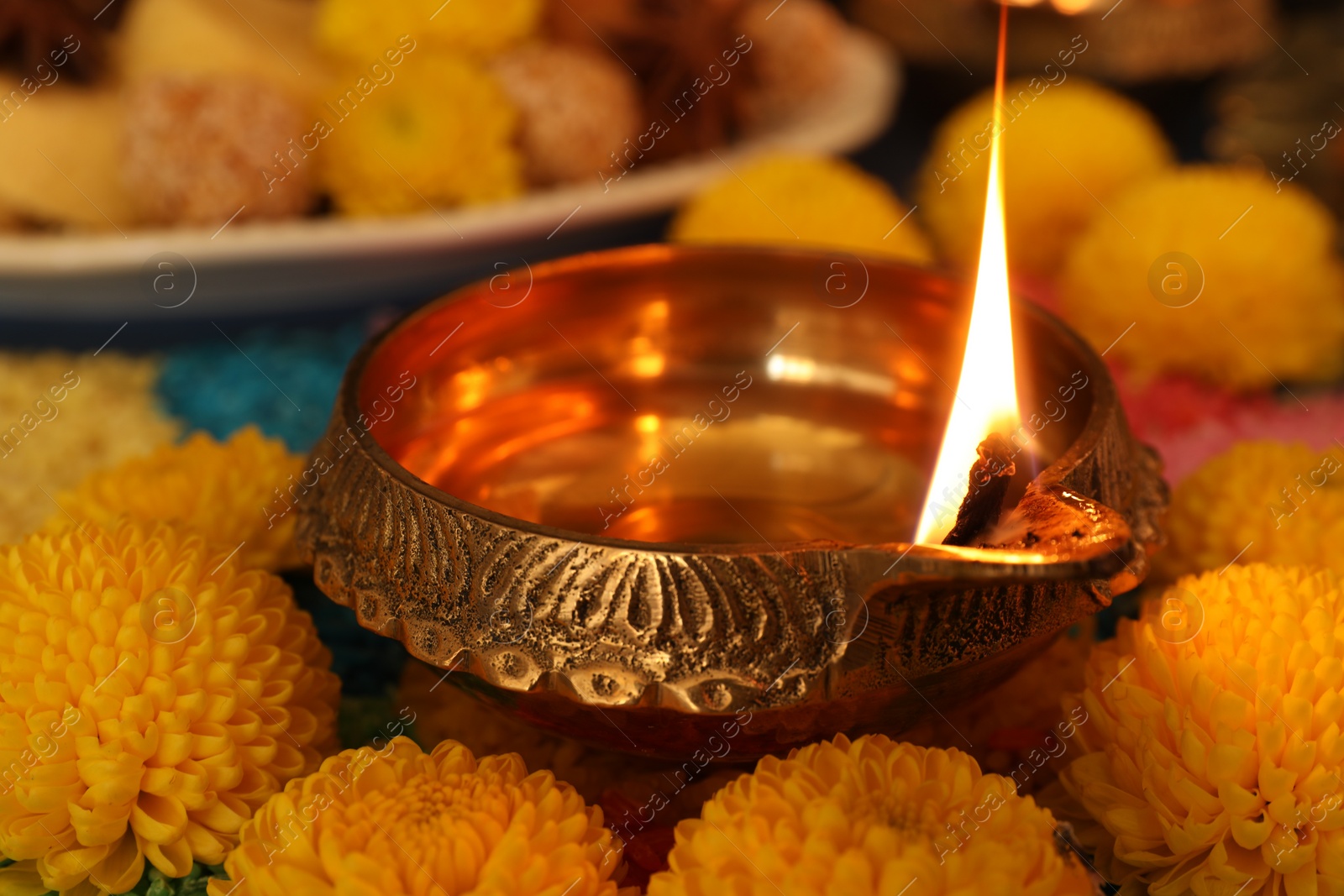 Photo of Diwali celebration. Diya lamp and chrysanthemum flowers on table, closeup