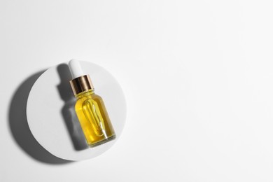 Bottle of cosmetic oil on white background, top view. Space for text