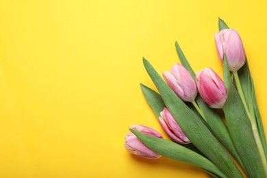 Photo of Pink tulips on yellow background, flat lay. Space for text
