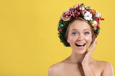 Photo of Pretty emotional young woman wearing Christmas wreath on yellow background. Space for text