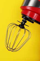 Closeup view of modern red stand mixer on yellow background