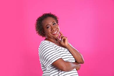 Photo of Portrait of happy African-American woman on pink background