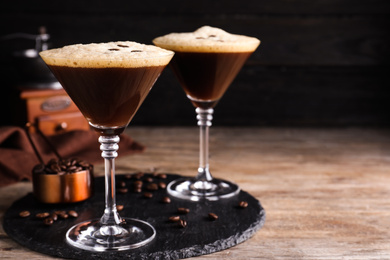 Photo of Glasses of fresh coffee cocktail on wooden table. Space for text
