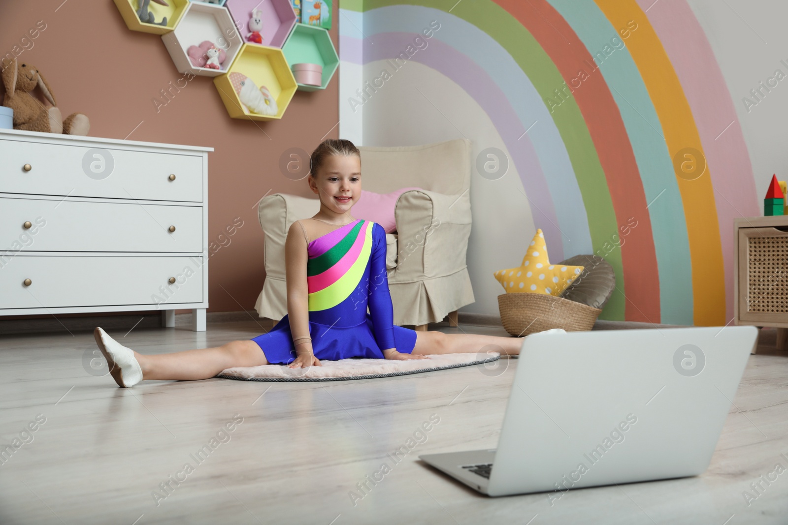 Photo of Cute little girl warming up before online dance class at home