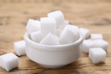 Photo of White sugar cubes on wooden table, closeup