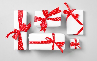 Photo of Christmas gift boxes with red bows on grey background, flat lay