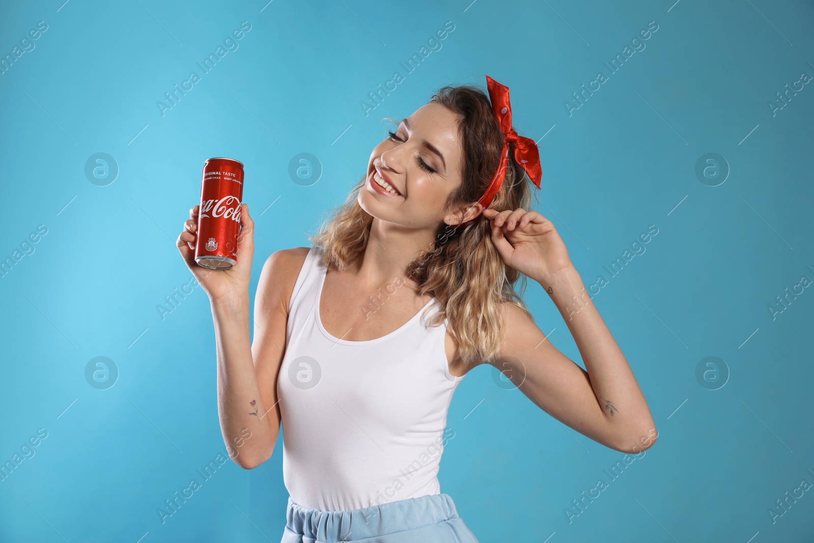 Photo of MYKOLAIV, UKRAINE - NOVEMBER 28, 2018: Young woman with Coca-Cola can on color background