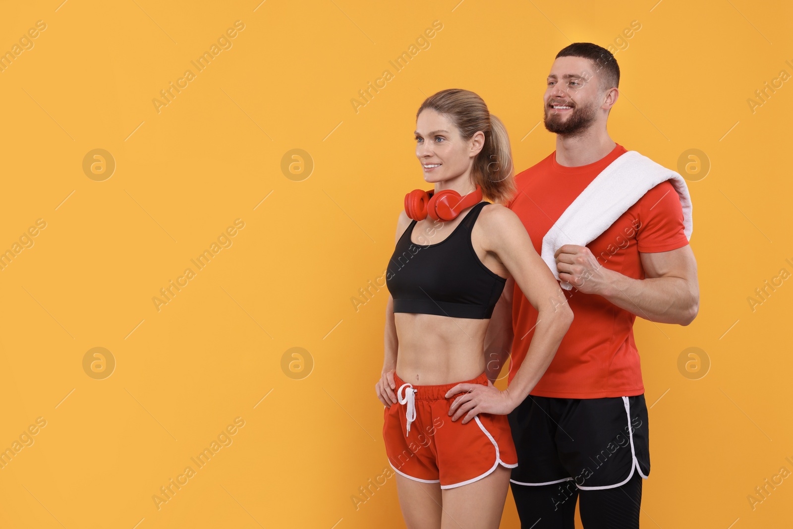 Photo of Athletic people with headphones and towel on yellow background, space for text