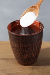 Photo of Adding baking soda into water at wooden table