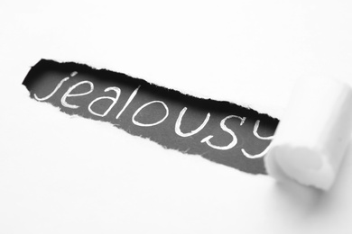 Photo of Word JEALOUSY under ripped paper as background