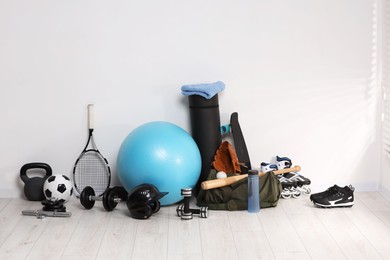 Photo of Many different sports equipment near wall indoors