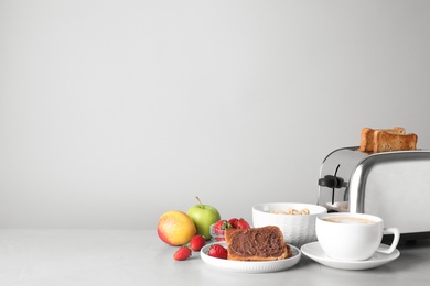 Photo of Healthy breakfast and modern toaster on light grey table, space for text