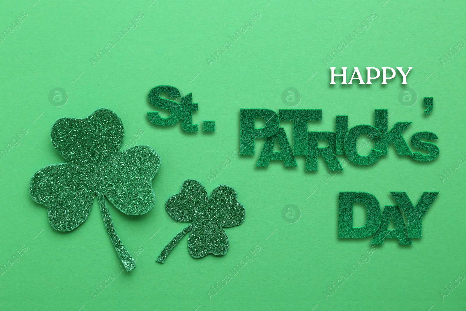 Image of Happy St. Patrick's day card. Text and decorative clover leaves on green background, top view