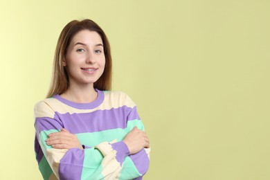 Portrait of smiling woman with dental braces on light green background. Space for text