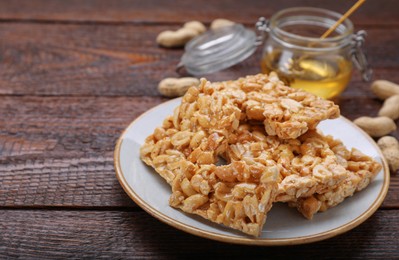 Photo of Delicious peanut bars (kozinaki) and ingredients on wooden table. Space for text