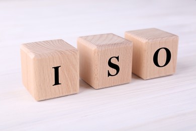 Photo of International Organization for Standardization. Cubes with abbreviation ISO on white wooden table, closeup